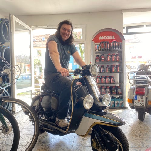 Leon sitzt auf einer Lambretta in der 2-radscheune 
